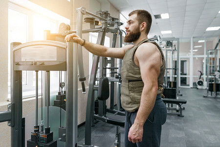 军事摄影照片_军事运动，肌肉发达的白种人留着胡子的成年男子在健身房锻炼