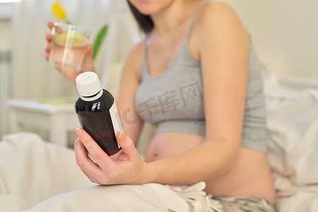 年轻孕妇手里拿着可溶性药物、维生素