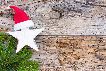 出现和圣诞装饰，星形、红色圣诞老人帽子和绿色杉树枝在木头上，顶视图