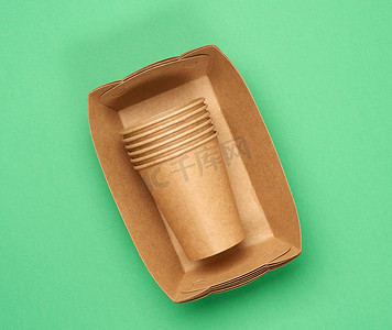 绿色背景上棕色工艺纸制成的纸盘和杯子