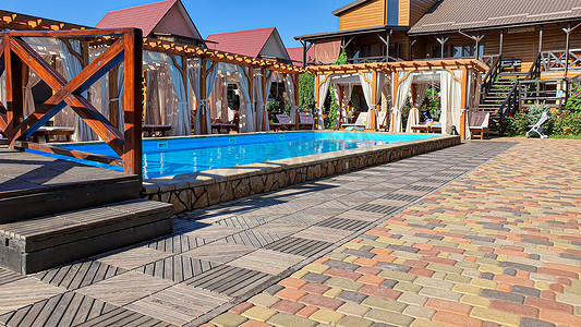 凉水摄影照片_庭院设有游泳池、日光浴躺椅和采用环保木材制成的游乐场。