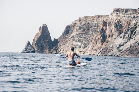 一名男子在冲浪板上游泳和放松的侧视图照片。