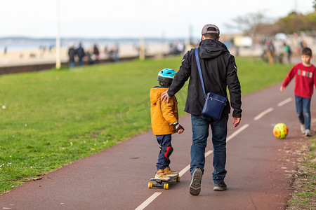 男孩和父亲在自行车道上学滑板