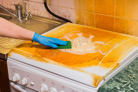 女人的家庭主妇手戴家用手套，洗厨房背景煤气灶上的脏涂层，特写