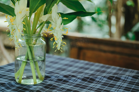 玻璃瓶中的白花和绿叶装饰在桌子上
