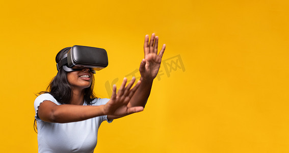 年轻的印度女性穿着虚拟现实模拟器，在黄色背景上打手势。