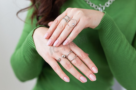 金色手环摄影照片_用时尚的浅粉色美甲闭合女性手，佩戴时尚的戒指首饰。