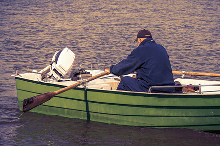 老人用桨后视图划船。