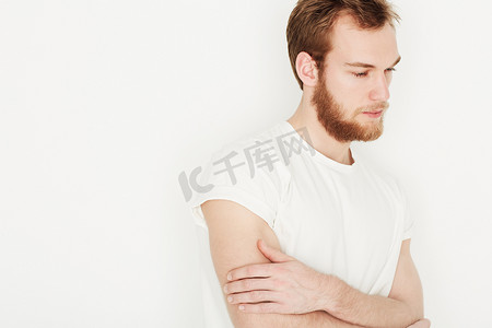 心情低落……一个穿着白色T恤的年轻人双手抱胸站着。