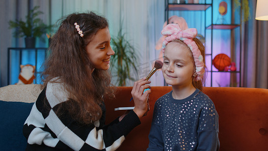 十几岁的孩子在家里游戏室帮助她的小妹妹做面部化妆