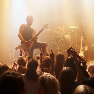 一位年轻吉他手在音乐会上为人群表演独奏的镜头。