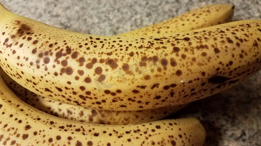 皮肤斑点摄影照片_柜台上有斑点的成熟香蕉果实