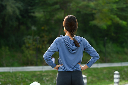 女跑步者在户外运动训练后休息的后视图。