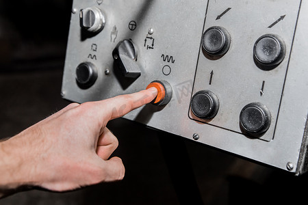 工人的手用手指按下工业设备旧系统和控制面板上的红色按钮