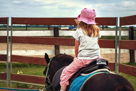 骑小马，年轻女孩作为骑师后视。