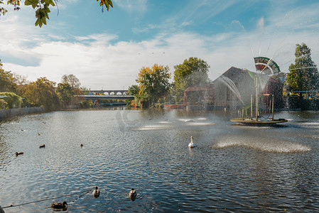 天鹅喷泉摄影照片_德国老欧洲城市比蒂格海姆-比辛根的城市喷泉和池塘，有天鹅和鸭子。
