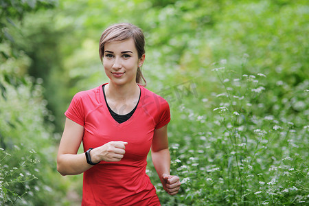 年轻的健身女人在早晨的森林小道上跑步。