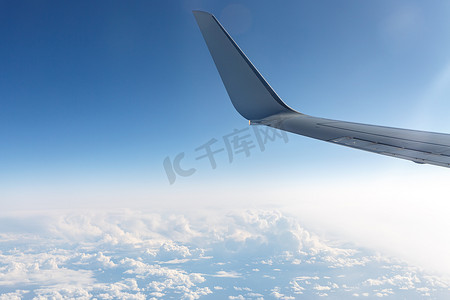 一架飞机的机翼在蓝云上方的天空中。
