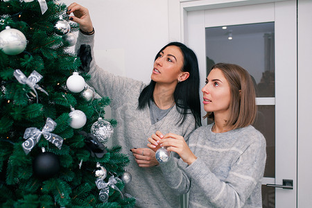 两名年轻女子装饰圣诞树，为新年庆祝活动做准备