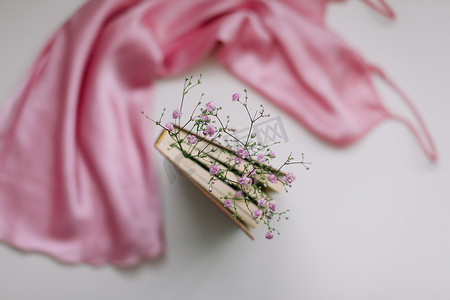 平躺组合物，白色背景顶视图上有优雅的粉色连衣裙、书籍、鲜花