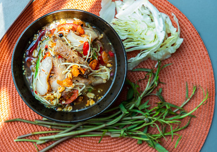 泰式木瓜辣沙拉（Som Tum）将烤猪颈肉混合在陶瓷盘子上。
