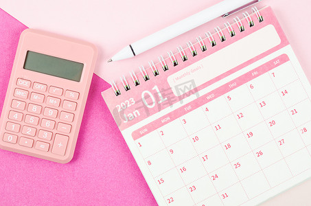 2023 年 2023 年 1 月台历，配有计算器和笔，粉红色背景。