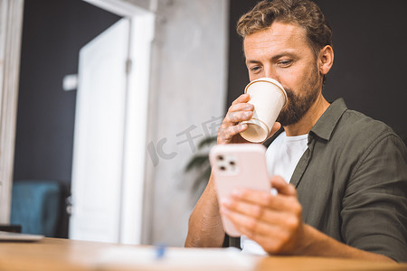 文案撰稿人一边在家喝咖啡，一边专注于手机。