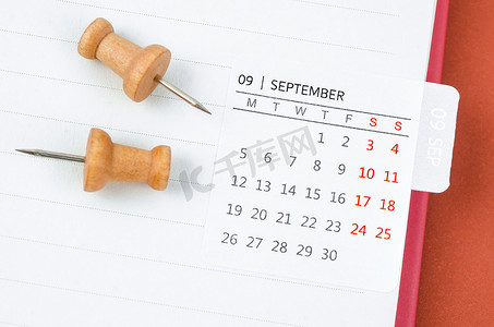 9月份摄影照片_迷你九月月历和开放日记上的木制图钉。
