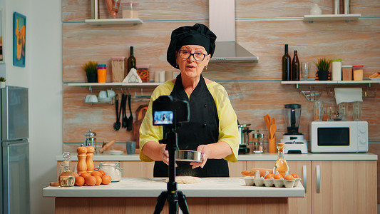视频播客摄影照片_老妇人拍摄烹饪视频博客