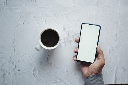 手机花屏摄影照片_拿着咖啡的CPU并使用带白屏的智能手机
