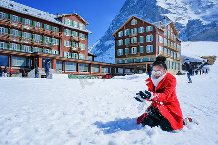 玩雪摄影照片_美丽的年轻女子穿着毛皮红色外套在户外玩雪
