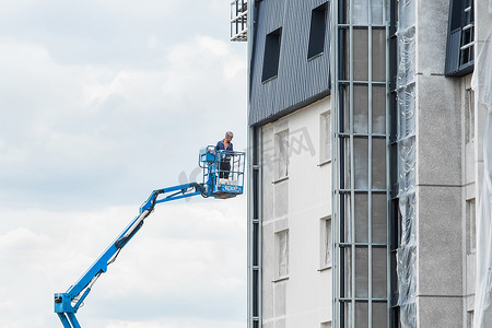 2020新高度摄影照片_白俄罗斯，明斯克 — 2020年5月28日：建筑工地一栋在建房屋新立面附近的升降平台上的产业工人