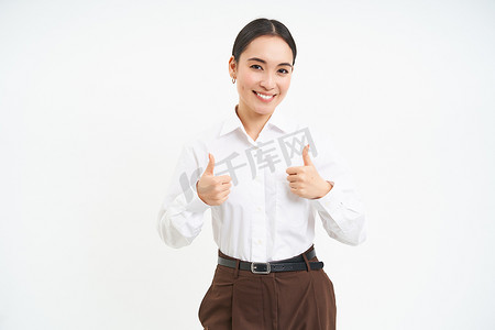 微笑的亚洲女性竖起大拇指，批准促销优惠，推荐产品，在白色背景中孤立站立