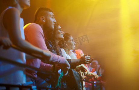 观众、粉丝在舞台摇滚活动的围栏上观看音乐会和音乐节，灯光、模型和人群。