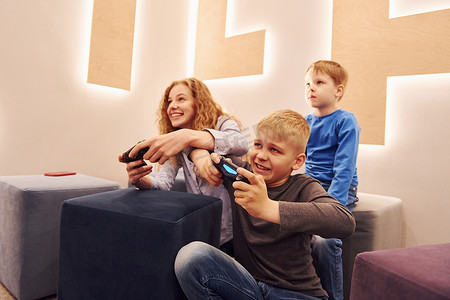 快乐的孩子们坐在室内一起玩电子游戏