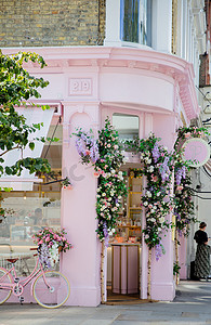 粉红色蛋糕店入口的肖像视图，外面有鲜花和自行车