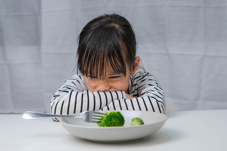 孩子生气摄影照片_孩子不喜欢吃蔬菜。