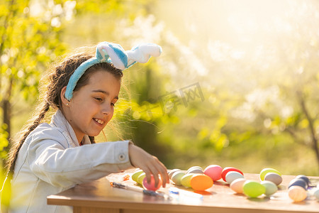 快乐的少女在花园里戴着兔子耳朵和复活节彩蛋