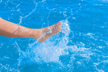水花喷出摄影照片_一个年轻女孩的腿喷出蓝光海水特写。
