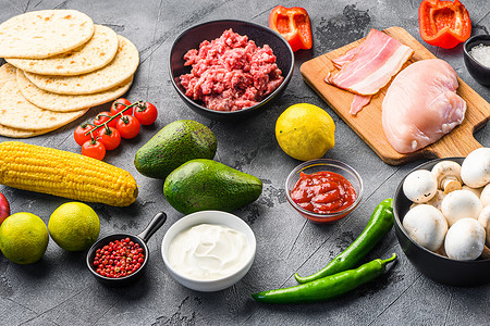 塔科配料自制烹饪，包括蔬菜、鸡肉、牛肉和猪肉、玉米、蘑菇，灰色背景侧视图。