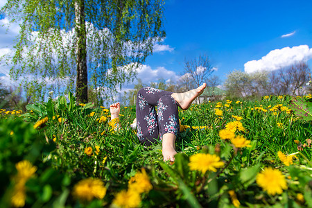 春天蒲公英摄影照片_孩子的脚踩在春天蒲公英花园的草地上。