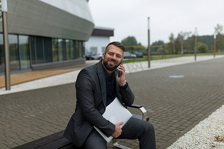 一位成功的欧洲男记者手里拿着笔记本电脑，在商务中心的背景下远程工作