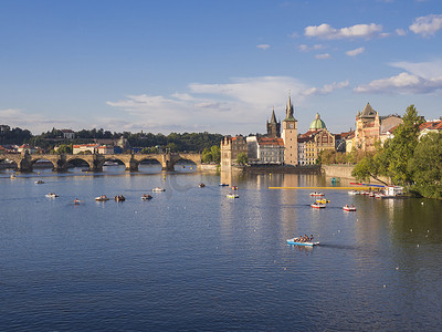 伏尔塔瓦河上的查理大桥和捷克共和国布拉格老城区的房屋全景，黄金时段的灯光，夏日阳光明媚的日子，游客在脚踏船上放松