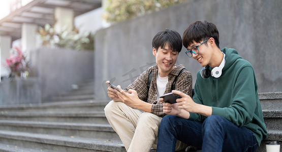 快乐的男人摄影照片_快乐的亚洲男大学生与朋友在智能手机上玩手机游戏