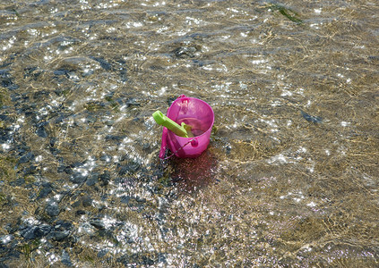 大桃摄影照片_浅水中的玩具桶和铲子