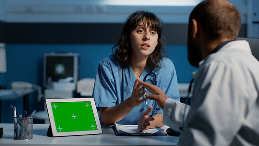 助理在使用绿屏模板分析平板电脑时与医生讨论患者专业知识