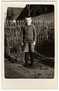 老式照片显示小男孩学生，学生站在木栅栏前。