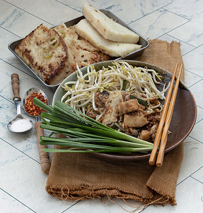 将豆芽和韭菜放入陶瓷盘中炒软萝卜糕或炒萝卜糕（柴头粿）。