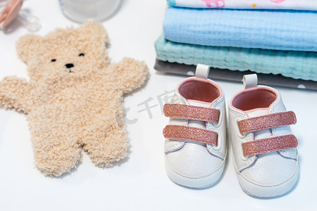 女婴粉红色鞋子与其他新生儿配件在白色表面。