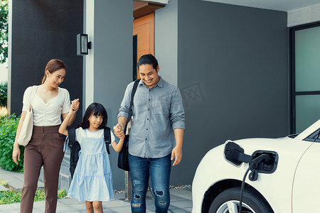 进步的年轻父母和女儿住在一个有电动汽车的家里。